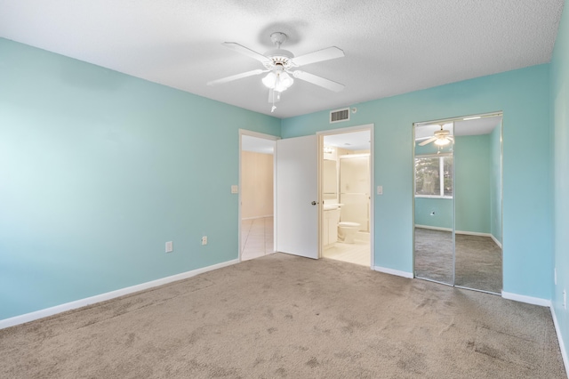 unfurnished bedroom with carpet, a closet, a textured ceiling, baseboards, and connected bathroom