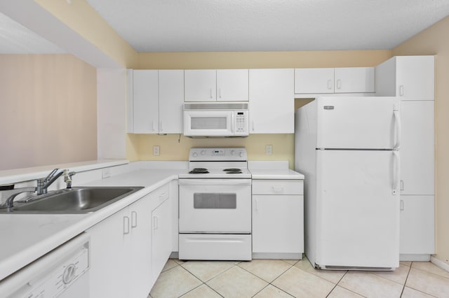 kitchen with white appliances, a sink, light countertops, light tile patterned floors, and white cabinetry