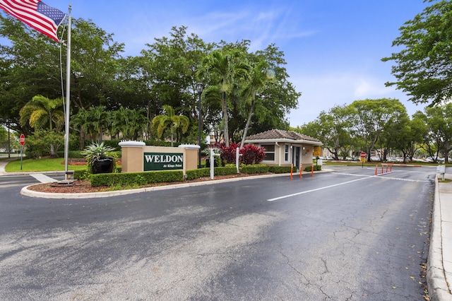 view of asphalt street with traffic signs, a gated entry, and curbs