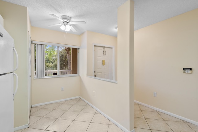 unfurnished room featuring a ceiling fan, a textured ceiling, light tile patterned flooring, and baseboards