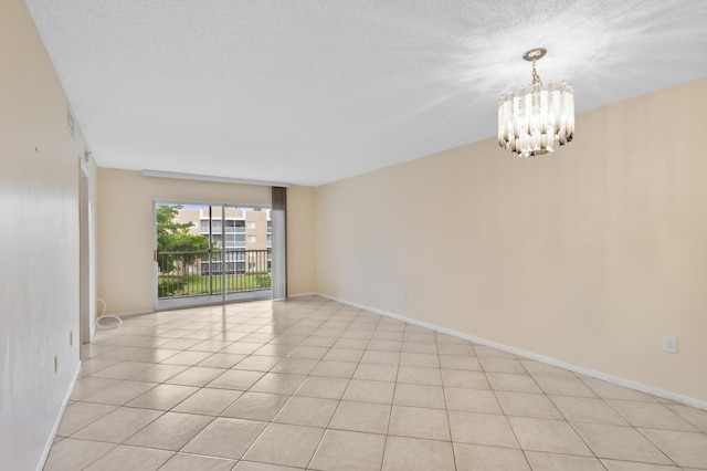 empty room with a chandelier, baseboards, and light tile patterned flooring