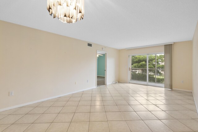 unfurnished room featuring a chandelier, baseboards, and light tile patterned floors