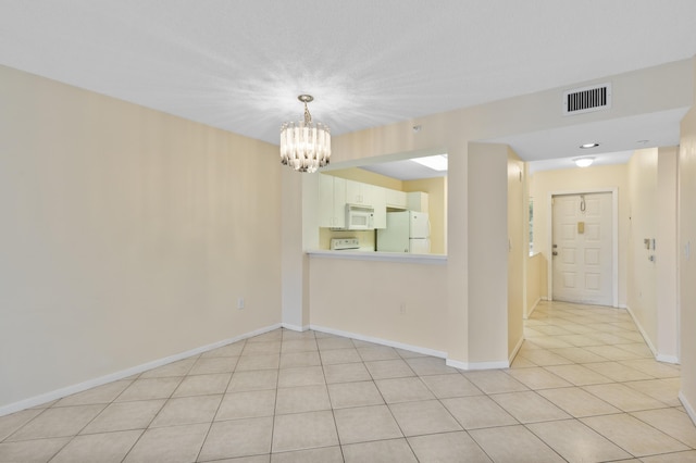 spare room featuring a chandelier, light tile patterned floors, and baseboards