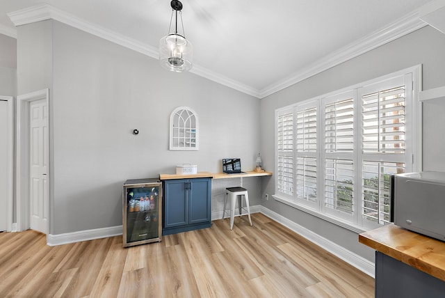 office area featuring beverage cooler, baseboards, light wood-style flooring, and crown molding