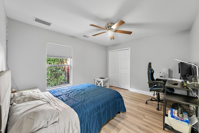 bedroom featuring a desk, light wood-type flooring, a closet, a ceiling fan, and baseboards