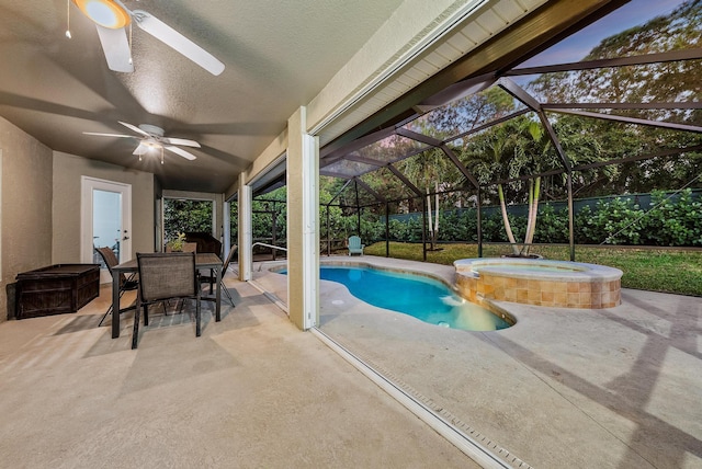 view of swimming pool featuring ceiling fan, a patio area, outdoor dining area, a pool with connected hot tub, and glass enclosure