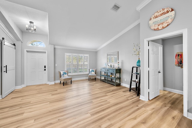 entryway with a barn door, lofted ceiling, light wood-style floors, crown molding, and baseboards