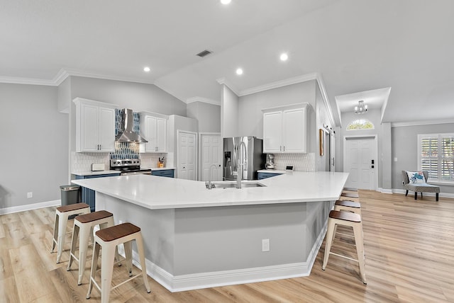 2160 SW Panther Trce, Stuart, FL 34997 - kitchen featuring stainless steel appliances, a breakfast bar area, wall chimney range hood, white cabinetry, and vaulted ceiling