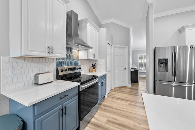 kitchen with stainless steel appliances, wall chimney range hood, ornamental molding, blue cabinetry, and white cabinetry