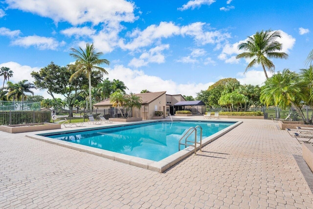 community pool with a patio area and fence