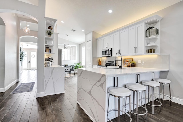 kitchen featuring open shelves, stainless steel appliances, a peninsula, arched walkways, and recessed lighting
