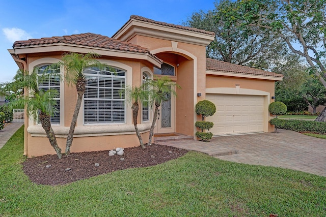 mediterranean / spanish-style home with an attached garage, decorative driveway, a tile roof, stucco siding, and a front lawn