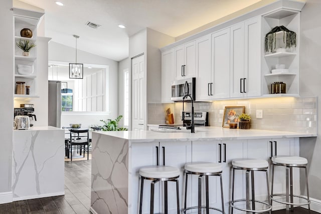 kitchen with open shelves, stainless steel appliances, a peninsula, white cabinets, and vaulted ceiling