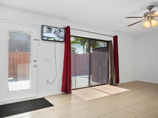 entrance foyer featuring ceiling fan, light tile patterned floors, a textured ceiling, and baseboards