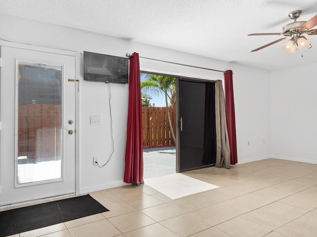 entrance foyer with ceiling fan, a textured ceiling, light tile patterned flooring, and baseboards