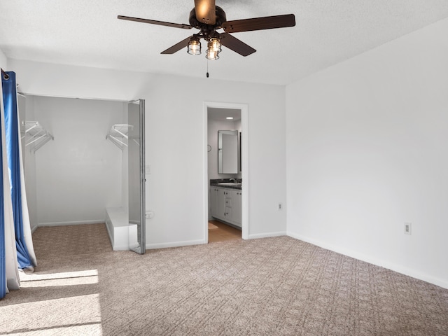 unfurnished bedroom with carpet, a sink, connected bathroom, baseboards, and ceiling fan