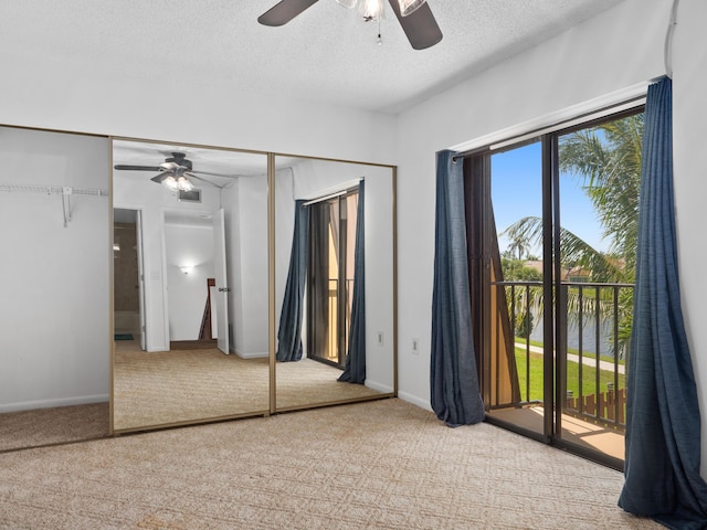 unfurnished bedroom with light colored carpet, access to exterior, a textured ceiling, and ceiling fan