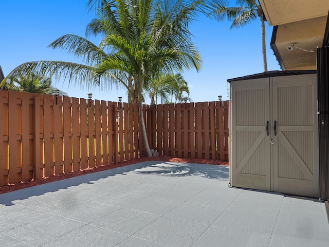 view of patio with a storage shed, an outbuilding, and a fenced backyard