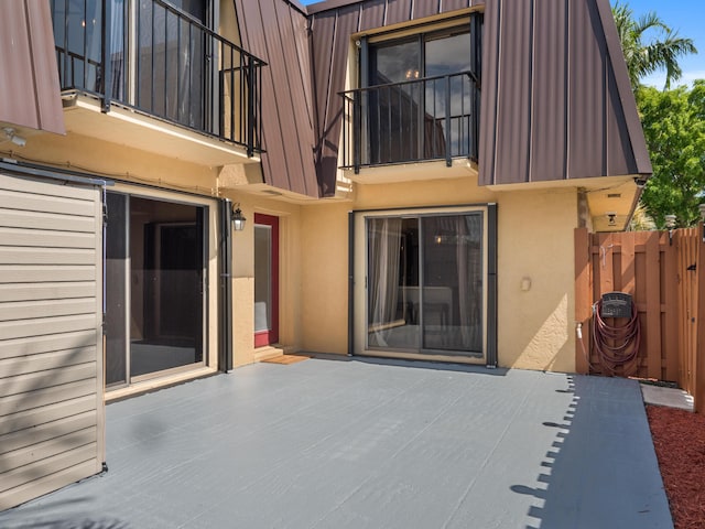 rear view of house with stucco siding, a balcony, fence, and a patio area