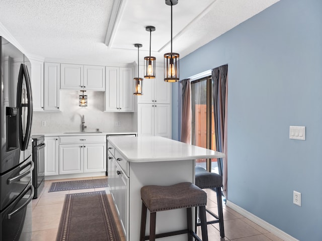 kitchen with stainless steel refrigerator with ice dispenser, black range with electric cooktop, a sink, light tile patterned floors, and light countertops