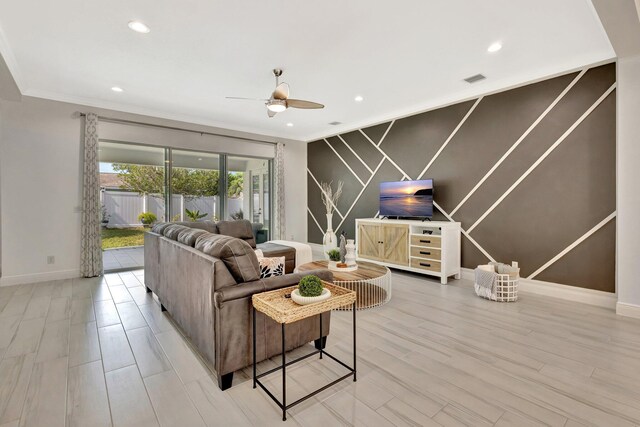 living area with an accent wall, baseboards, ceiling fan, ornamental molding, and recessed lighting
