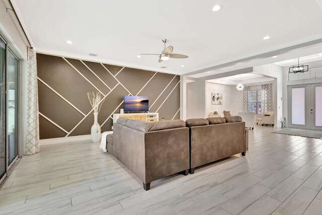 living room featuring a chandelier, recessed lighting, light wood-style floors, an accent wall, and ornamental molding