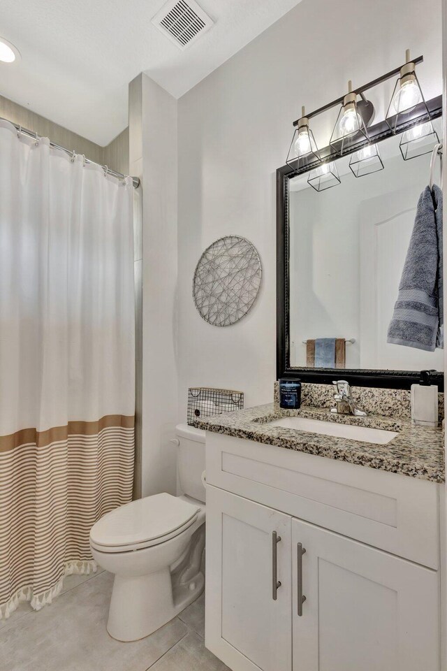 bathroom with toilet, vanity, curtained shower, and tile patterned flooring