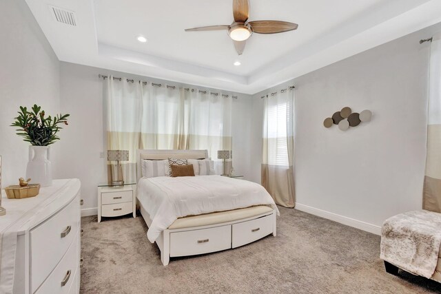 bedroom featuring a raised ceiling, light carpet, baseboards, and recessed lighting