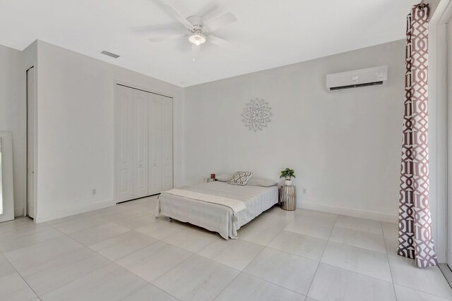 bedroom with an AC wall unit, a closet, a ceiling fan, and light tile patterned flooring