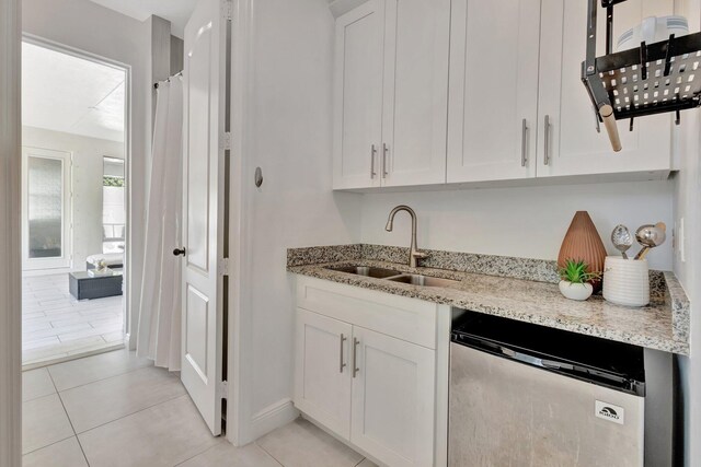 kitchen featuring dishwasher, a sink, and white cabinets