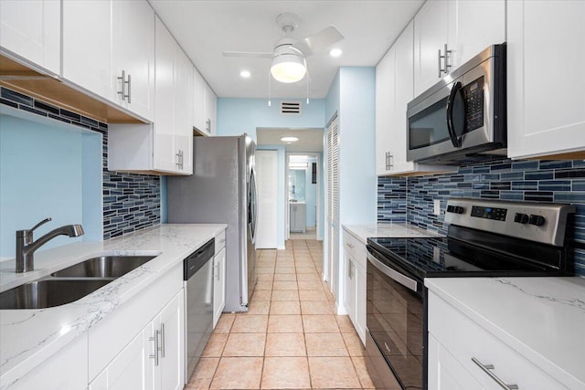 kitchen featuring appliances with stainless steel finishes, a sink, ceiling fan, light tile patterned floors, and white cabinets