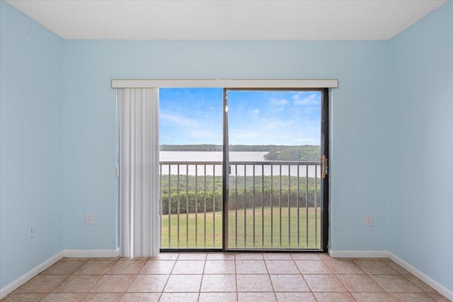 unfurnished room featuring a water view, baseboards, and light tile patterned floors