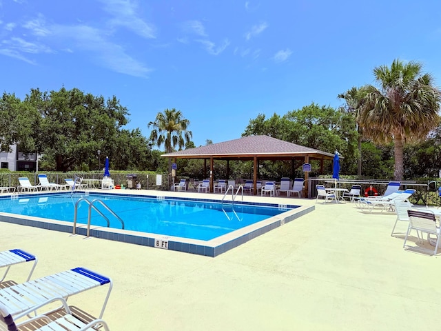 community pool with a gazebo, fence, and a patio area