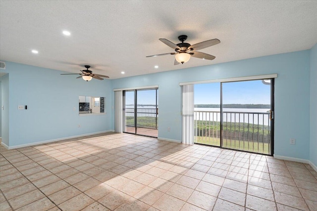 unfurnished room featuring a ceiling fan, a water view, light tile patterned floors, recessed lighting, and baseboards