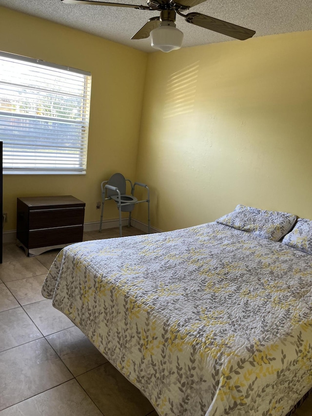 bedroom featuring a textured ceiling, tile patterned floors, ceiling fan, and baseboards