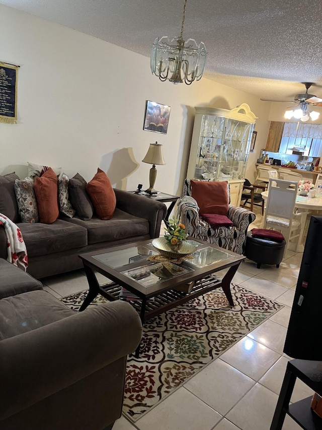 living room featuring a chandelier, light tile patterned flooring, a textured ceiling, and a ceiling fan