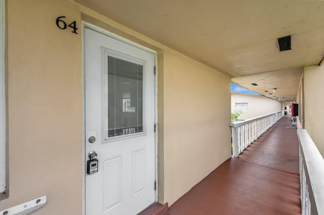 view of exterior entry with stucco siding and a balcony
