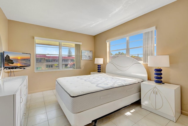 bedroom with multiple windows, light tile patterned flooring, and baseboards