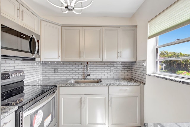 kitchen with stainless steel appliances, a sink, a chandelier, and backsplash