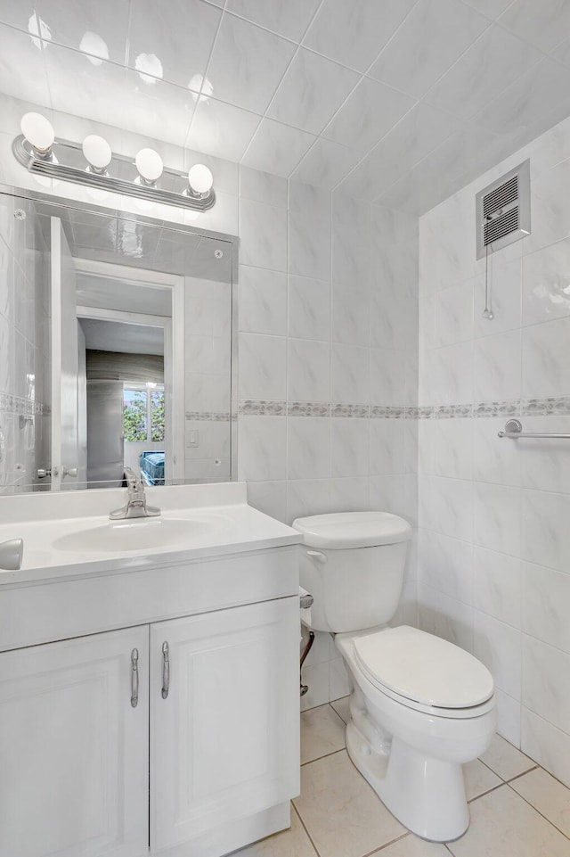 bathroom featuring tile patterned flooring, vanity, tile walls, and toilet