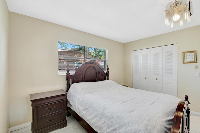 bedroom featuring a chandelier, baseboards, light tile patterned floors, and a closet