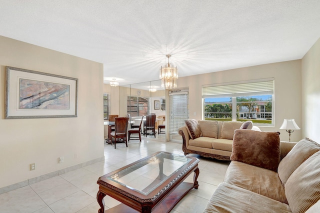 living room featuring a chandelier, light tile patterned flooring, baseboards, and a textured ceiling