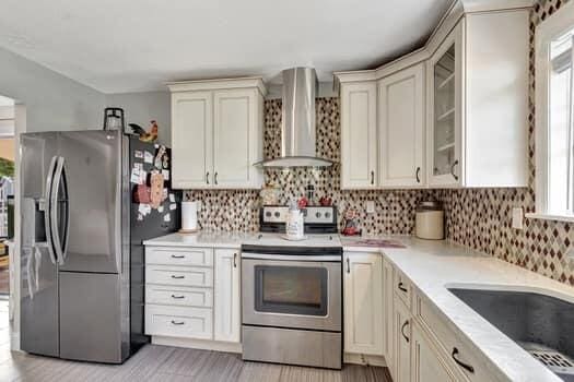 701 SW 1st Ave S, Boynton Beach, FL 33426 - kitchen featuring stainless steel appliances, wall chimney exhaust hood, tasteful backsplash, and healthy amount of natural light