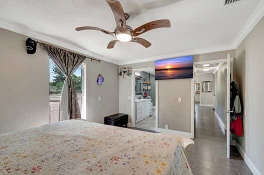 701 SW 1st Ave S, Boynton Beach, FL 33426 - bedroom with ornamental molding, baseboards, wood finished floors, ceiling fan, and ensuite bath