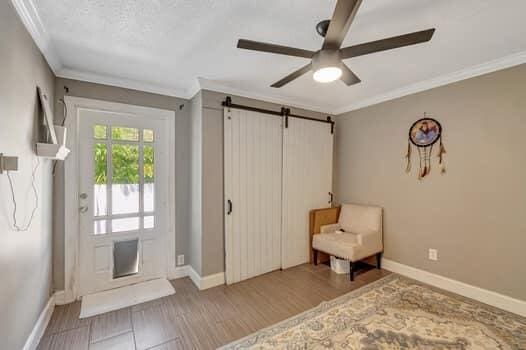 701 SW 1st Ave S, Boynton Beach, FL 33426 - sitting room with a barn door, a ceiling fan, ornamental molding, baseboards, and wood finished floors