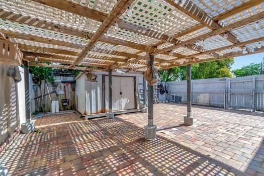 701 SW 1st Ave S, Boynton Beach, FL 33426 - view of patio featuring a storage unit, a fenced backyard, and an outbuilding