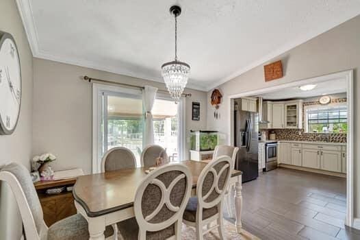 701 SW 1st Ave S, Boynton Beach, FL 33426 - dining space featuring ornamental molding, a chandelier, and vaulted ceiling