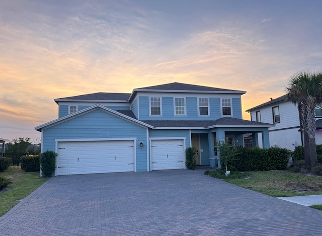 view of front of property with decorative driveway, fence, a shingled roof, and a garage