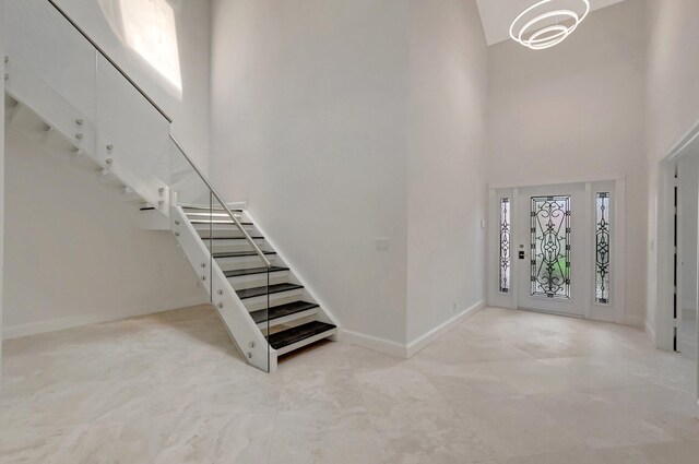foyer featuring a towering ceiling, baseboards, and stairs