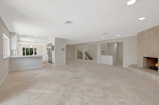 unfurnished living room featuring stairway, recessed lighting, baseboards, and a premium fireplace